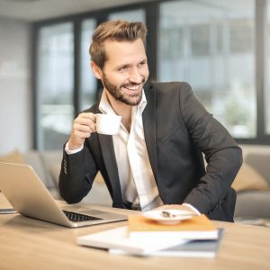 man-holding-white-teacup-in-front-of-gray-laptop-842567